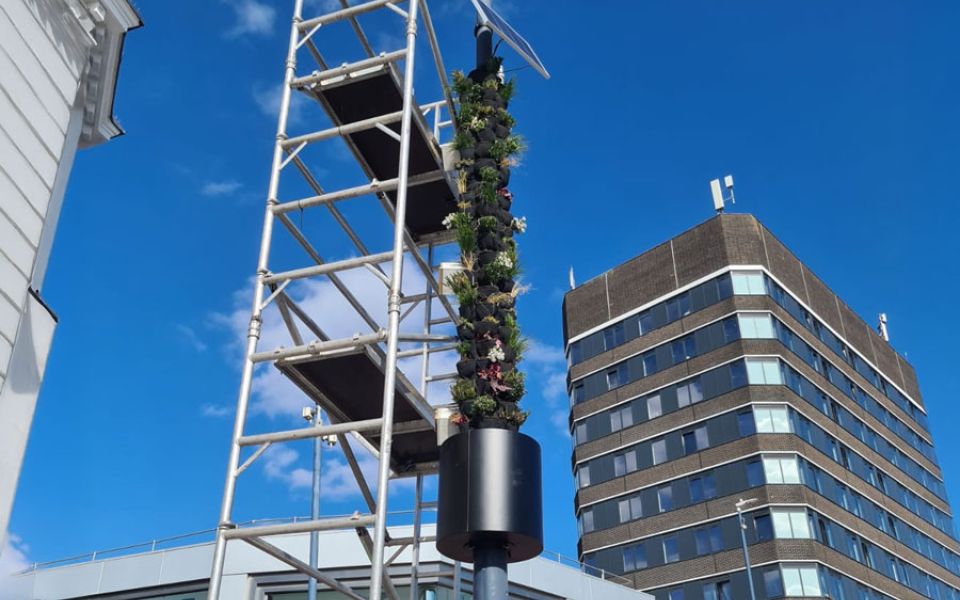 A tall tower adorned with various green plants growing along its structure.